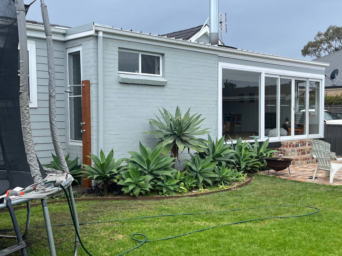 Backyard with outdoor shower, trampoline and fire pit